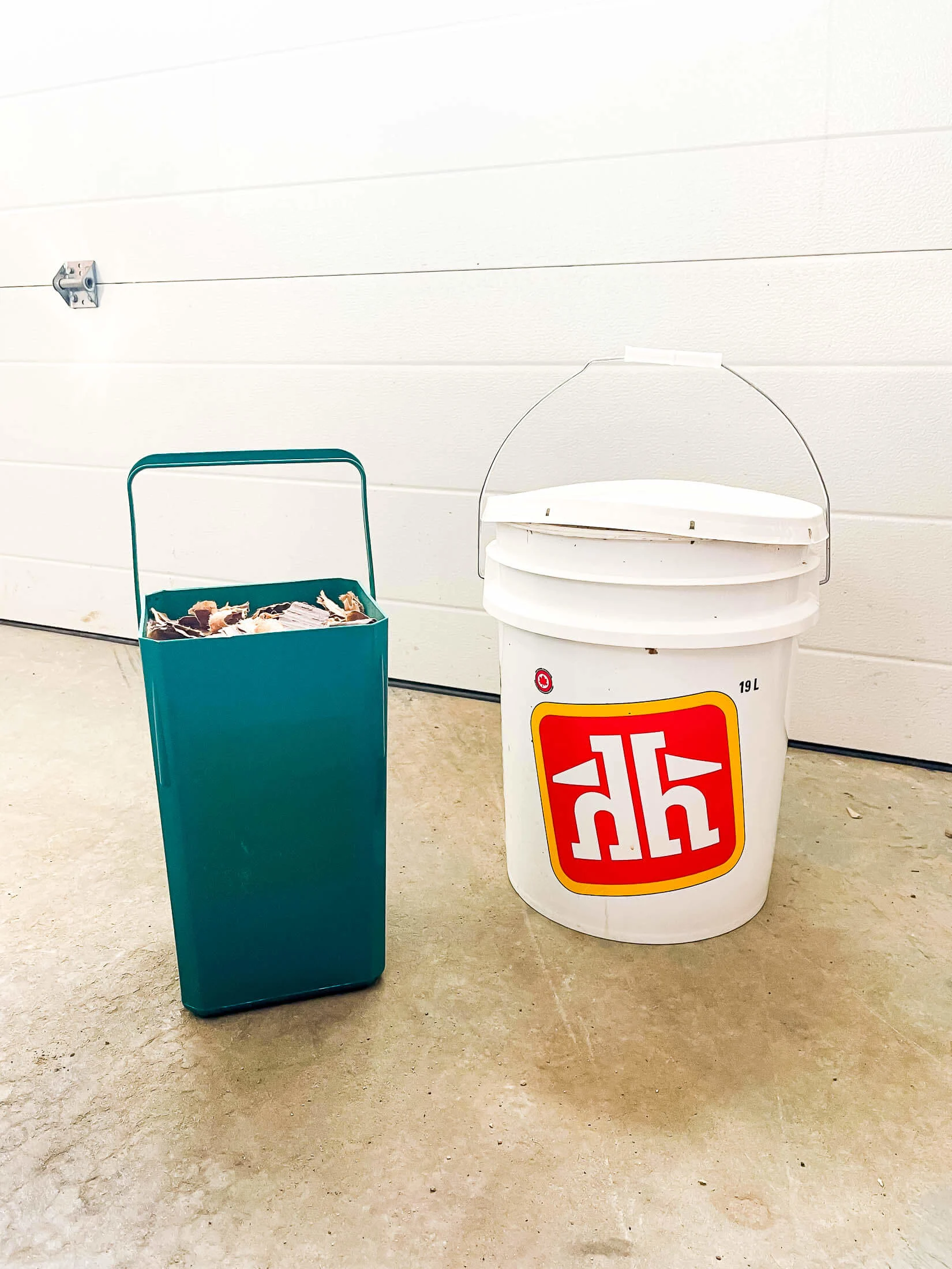 A kitchen compost bin and a 5 gallon bucket in the garage.