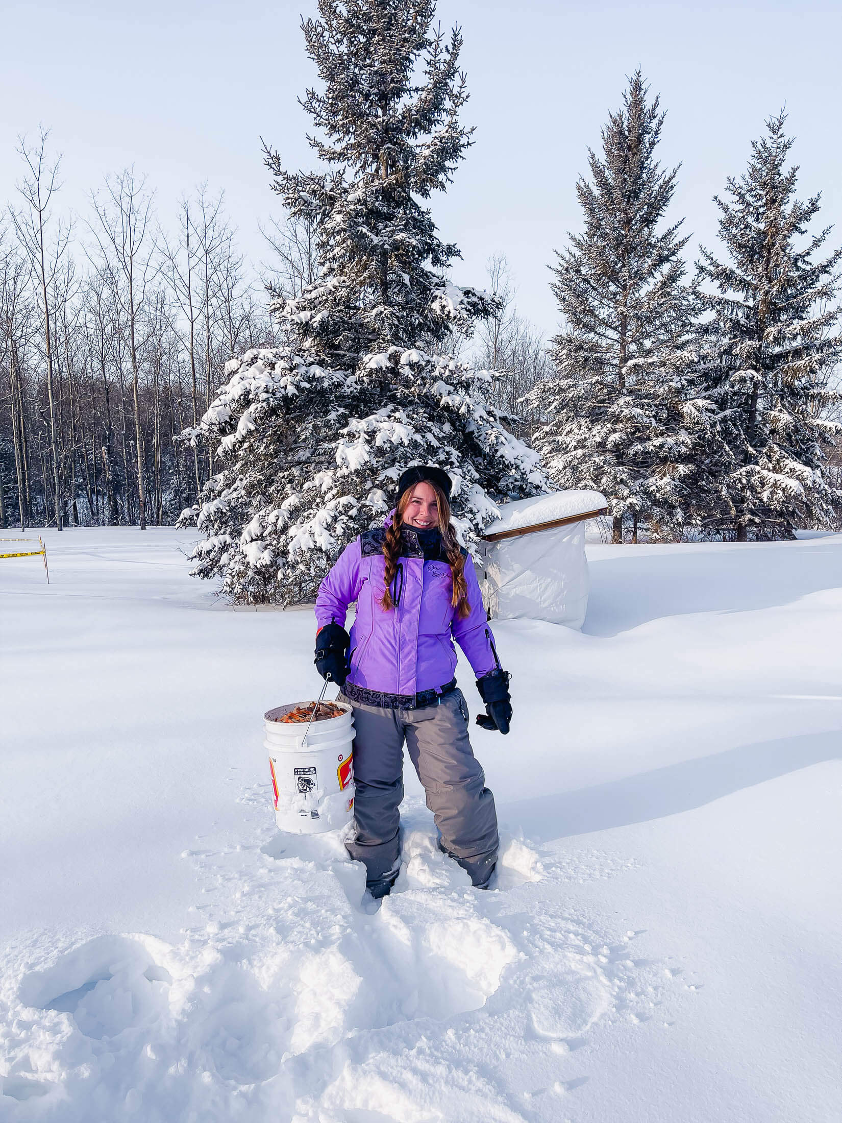 A woman holding a compost bucket in the snow. 
