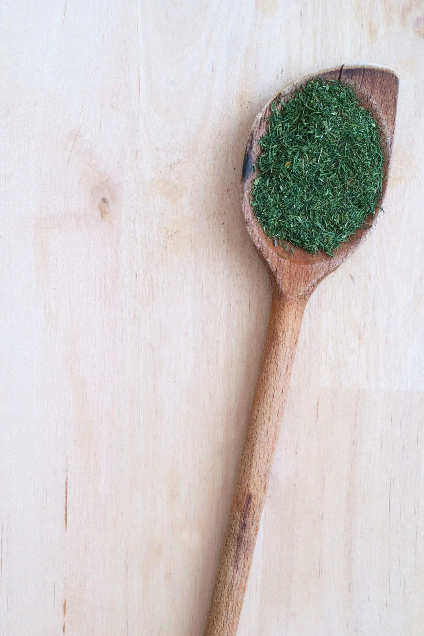 Dried dill in a wooden spoon.