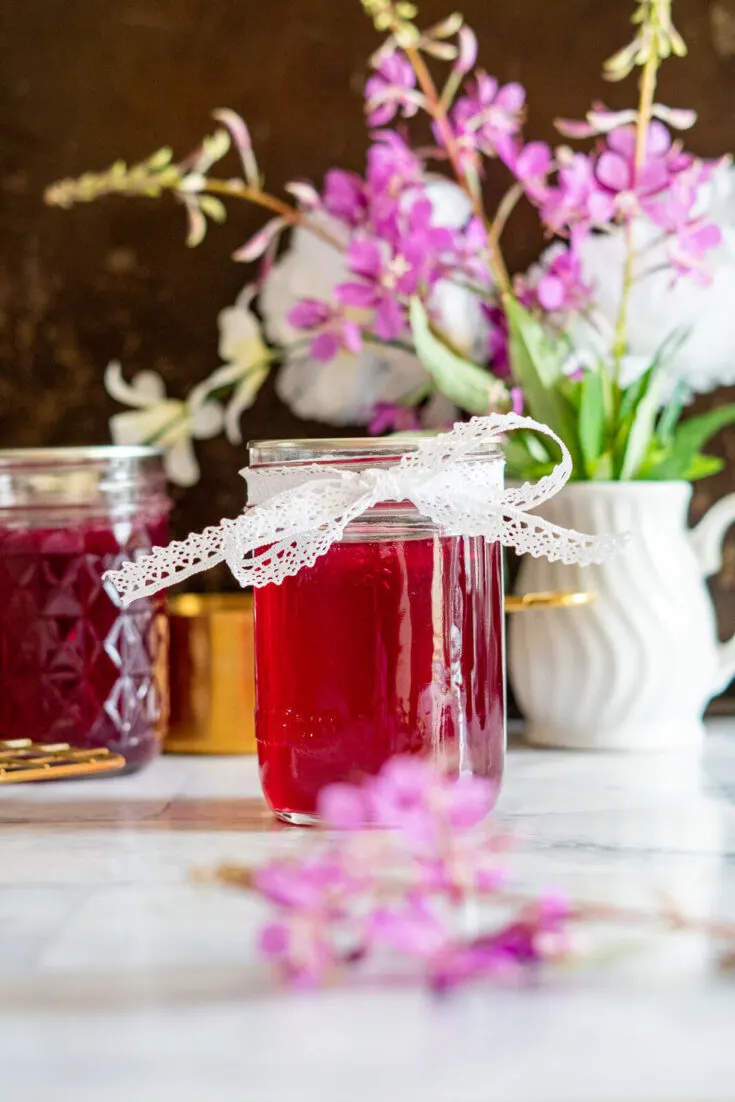 Jar of fireweed jelly tied with a bow.