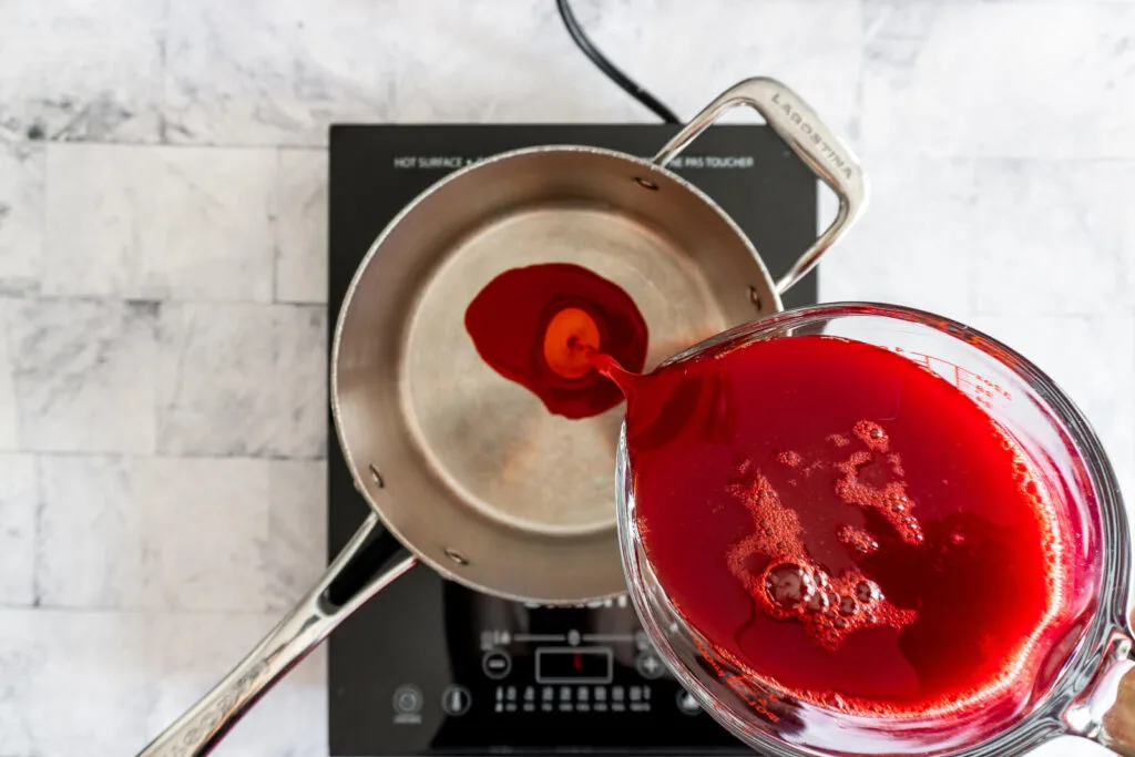 Pouring pin cherry juice into saucepan.