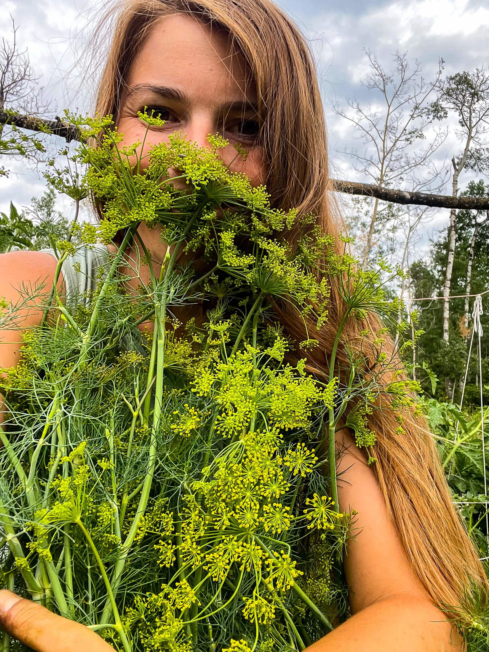 Woman hugging a flowering dill plant. 