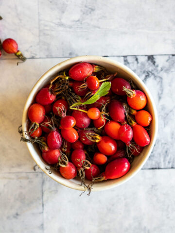 Rose hips in a white bowl.