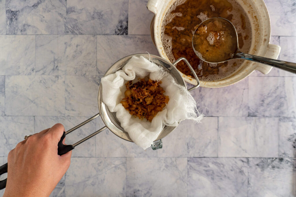 Straining tallow through cheese cloth.